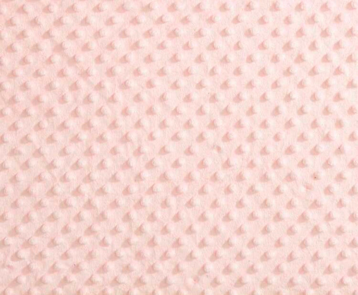 A close-up of a light pink textured fleece fabric with a repeating dotted or dimple pattern.