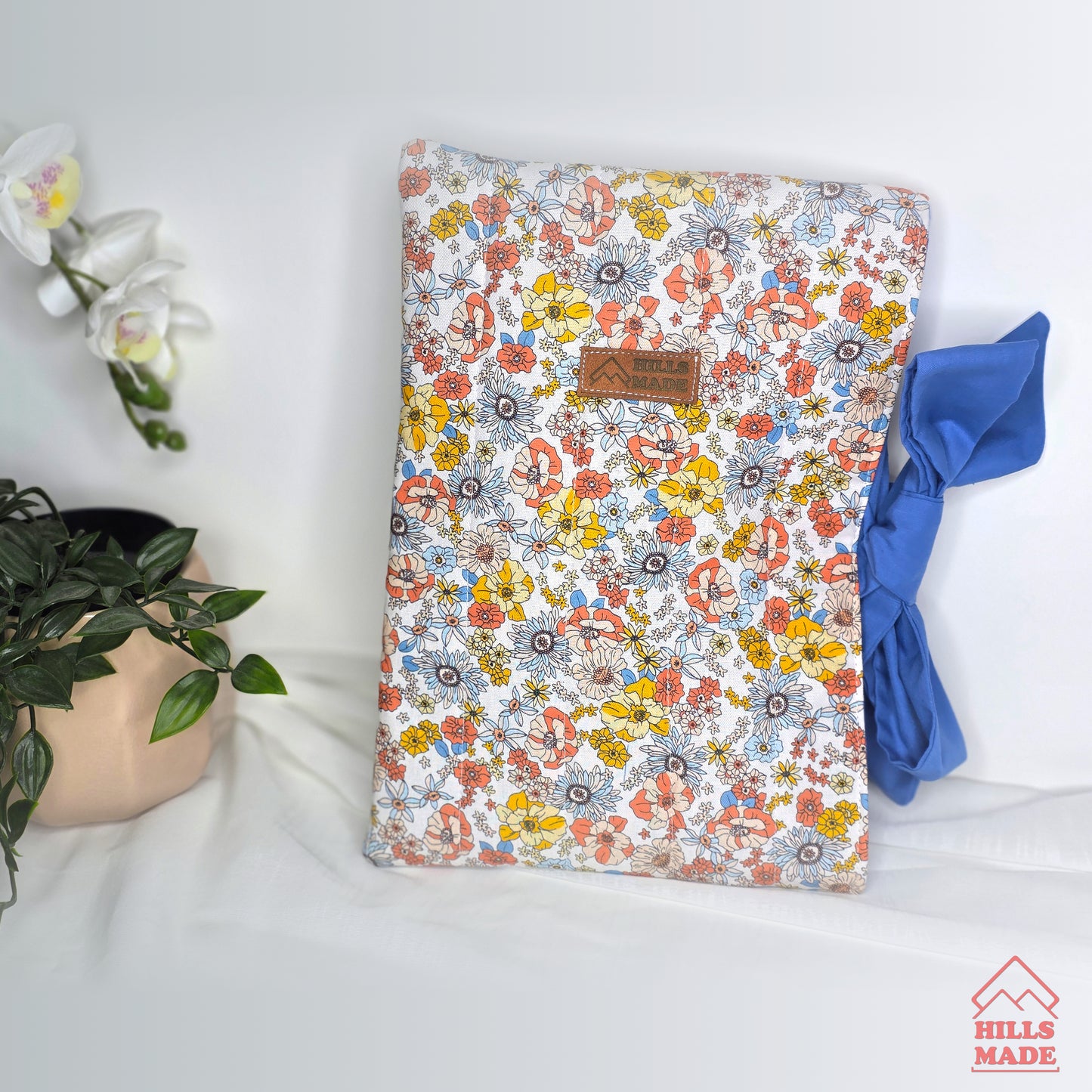 Floral-patterned book  sleeve with a plant and blue fabric on a white surface