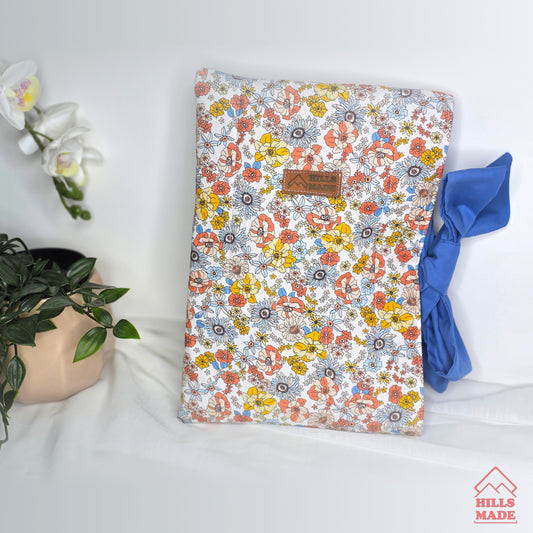 Floral-patterned book  sleeve with a plant and blue fabric on a white surface